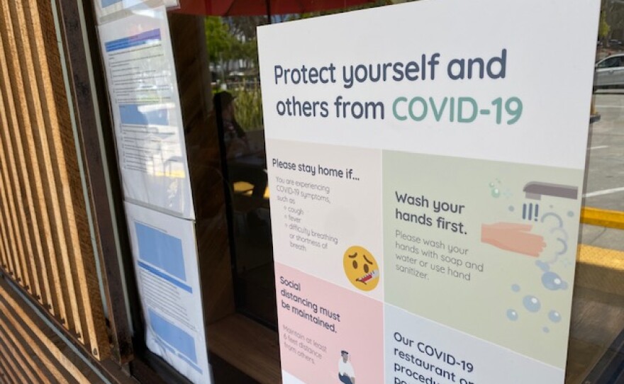 A sign detailing how to protect against COVID-19 outside of Rubicon Deli in La Jolla, Calif. July 21, 2020.