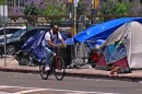 A man riding his bike through a homeless encampment in downtown San Diego, May 31, 2022.