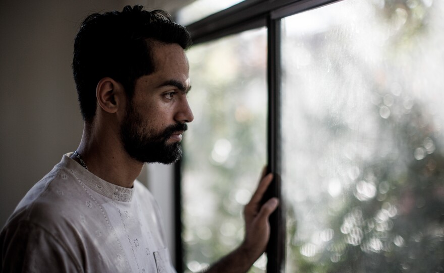 Afghan helicopter pilot Rashid Ahmad Muslim, 25, looks out the window at home in Chandler, Ariz., on Dec. 11, 2022.