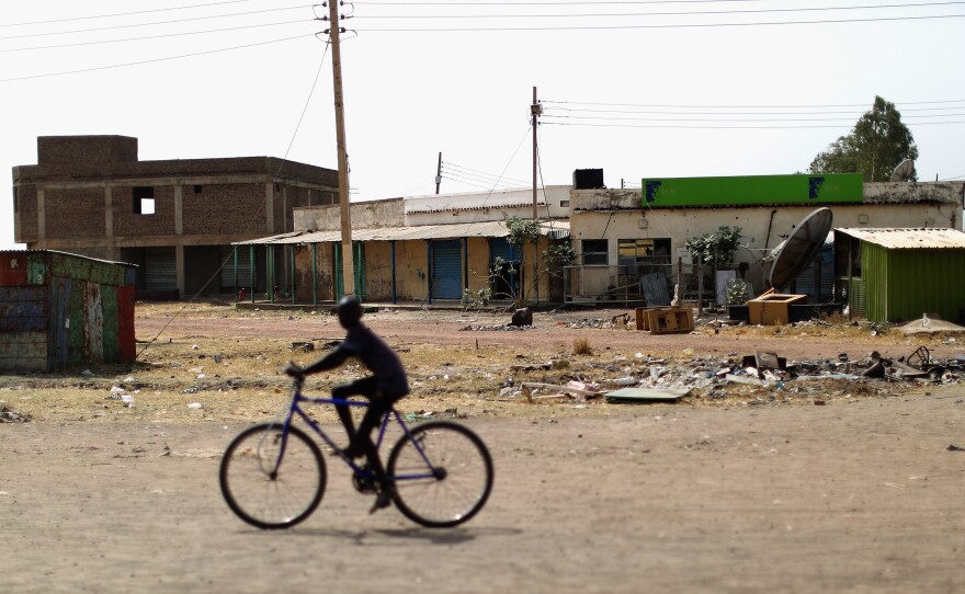 A child bikes along a main road in Bentiu. The town has been almost completely abandoned since the civil war began in 2013. Now some people are coming back, and pickup trucks serve as makeshift taxis.