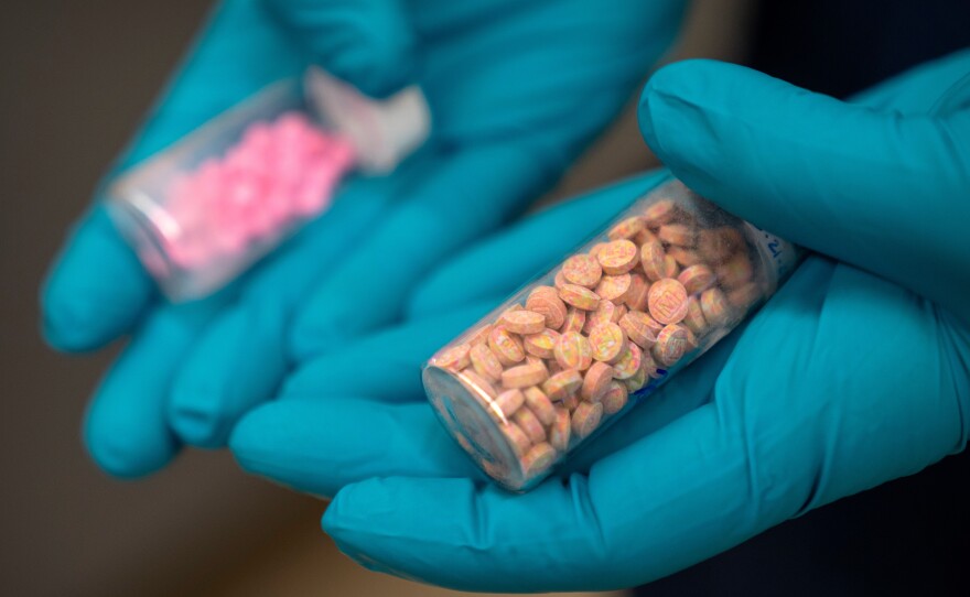 A forensic chemist with the Drug Enforcement Administration holds vials of fentanyl pills at a DEA research laboratory in this file photo. Fentanyl deaths are plunging in the U.S, but the recovery is threatened by a new "synthetic soup" of toxic street drugs.