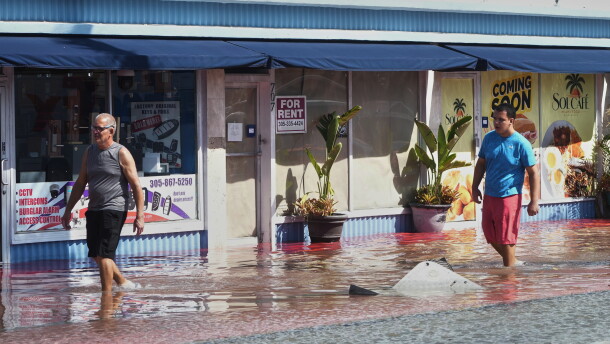 Pedestrians walk through a flooded street caused by king tides and heavy rain Wednesday, Oct. 28, 2026, in North Bay Village, Fla.