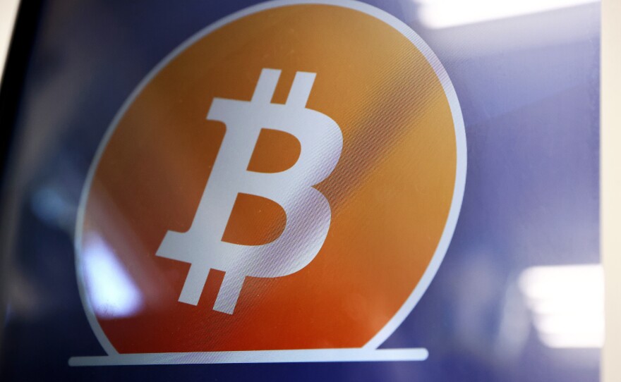 The Bitcoin logo is displayed on the screen of a Bitcoin ATM in Los Angeles. The Justice Department said a New York couple has been charged with conspiring to launder billions of dollars' worth of stolen bitcoin.