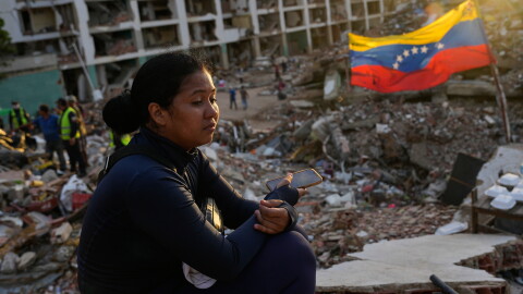 Estefany Landaez sits amid the rubble of a collapsed building in La Guaira, Venezuela, on July 12, 2026, as she waits for news about her two children following the earthquakes.
