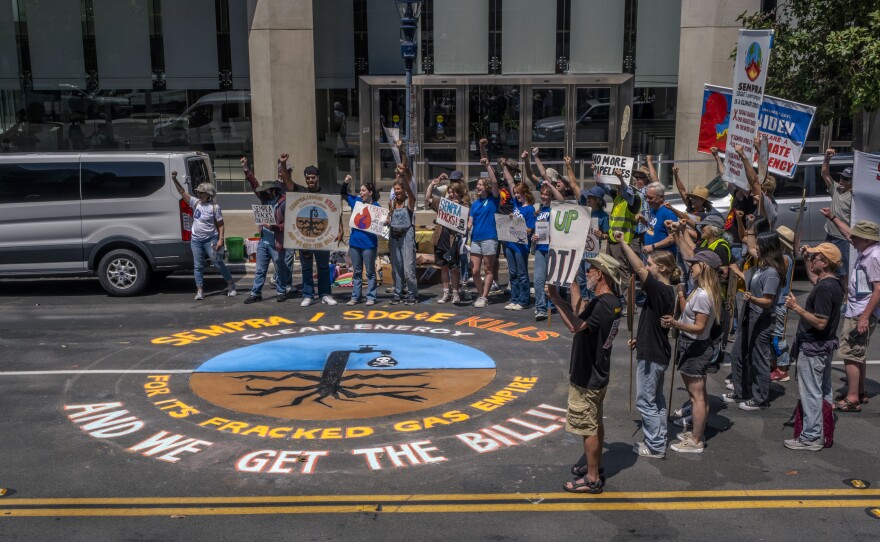 San Diego climate change activists rallied and created a large chalk drawing in the street in front of Sempra Energy headquarters in downtown San Diego, July 24, 2023.