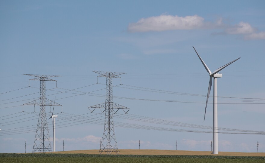 Power lines and power-generating windmills rise above the rural landscape on June 13, 2018, near Dwight, Ill. Driven by falling costs, global spending on renewable energy sources like wind and solar is now outpacing investment in electricity from fossil fuels and nuclear power.
