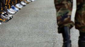 A drill sergeant passes a row of recruits -- many of them high school juniors and seniors -- headed into their first day of military life at the Army National Guard complex in Marseilles, Ill.