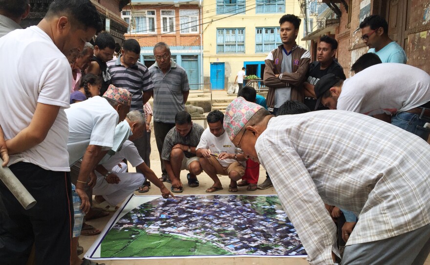 Residents of Panga, a town in Nepal hit hard by the 2015 earthquake, study a map of their area put together with drone images that Meier and his partners gathered.