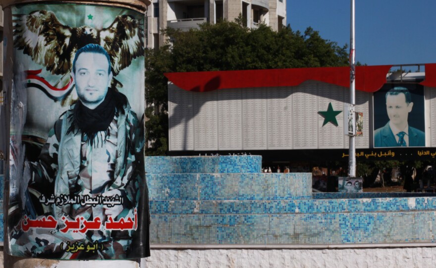 A poster memorializing a man who died fighting on the government's side is displayed in Tartus near a picture of Syrian President Bashar Assad at a memorial including a list of thousands of names of men killed in the war. The coastal city has a heavy population of Alawite Muslims, belonging to the same sect as Assad.