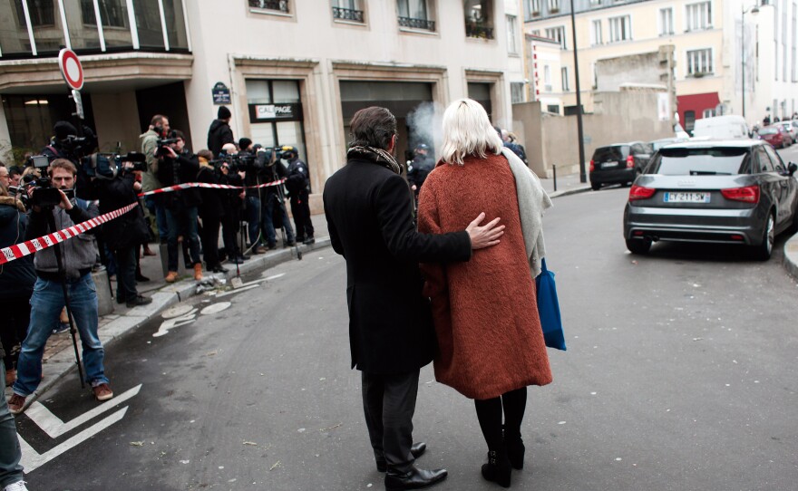 People stand outside the Charlie Hebdo office after the attack. NPR's Eleanor Beardsley says it's unclear how the gunmen managed to get past extra security, which had been put in place because of previous threats.