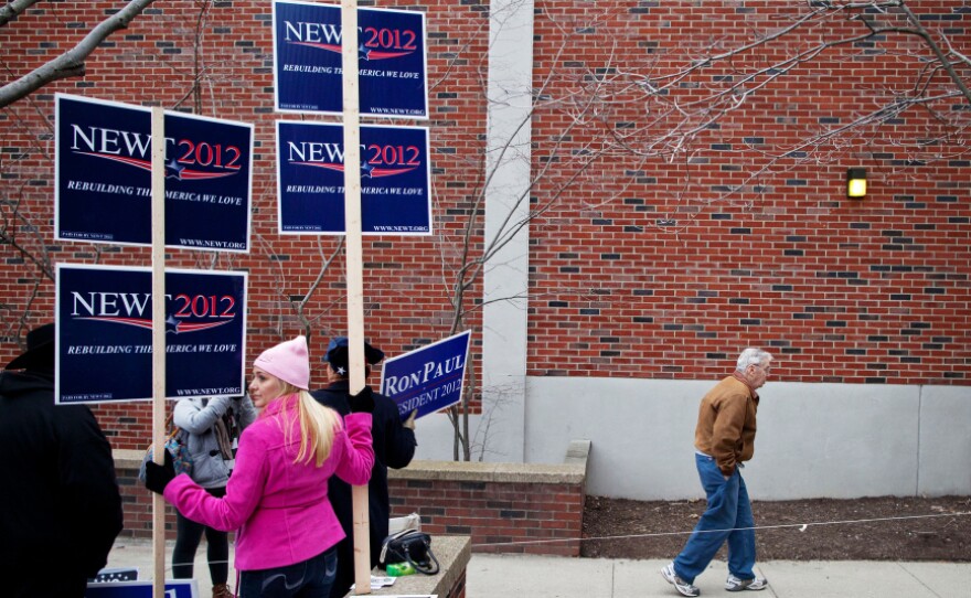 A man walks past campaign workers touting their candidates during voting in the New Hampshire primary, at Webster Elementary School in Manchester on Tuesday.
