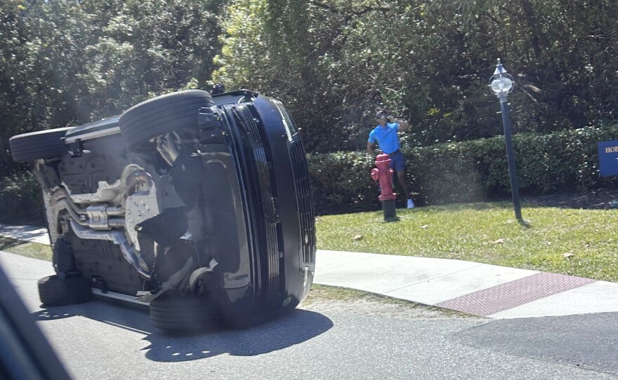 Golfer Tiger Woods stands by his overturned vehicle in Jupiter Island, Fla., on Friday, March 27, 2026.