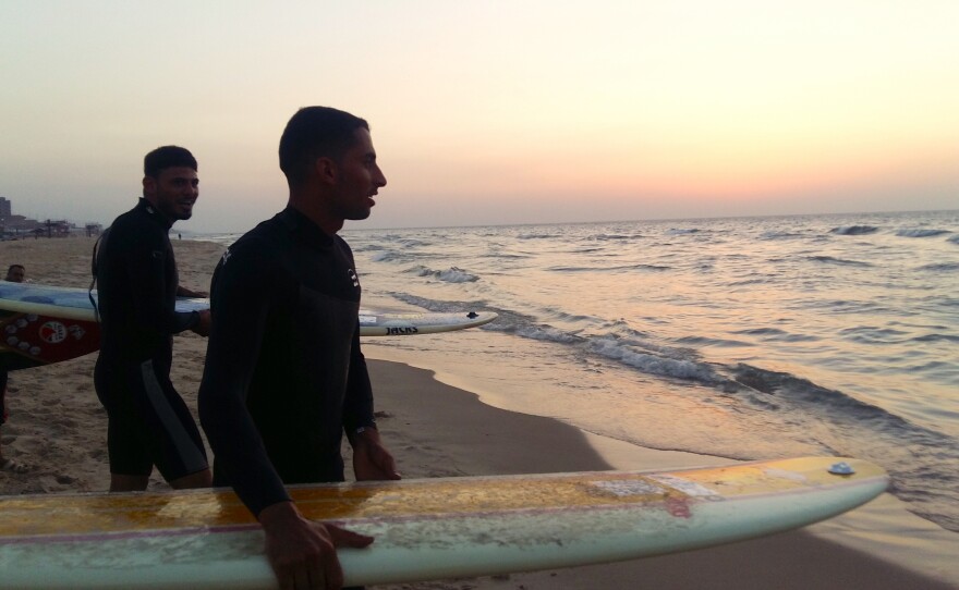 Ali Erheem (center) and his friend Tareg Naem get ready to plunge into the water at sunset in the Gaza Strip. They are members of an informal group of friends called the Gaza Surf Club, which was featured in a German documentary this year.