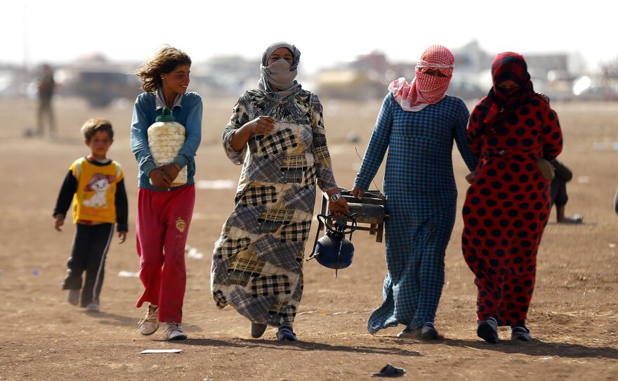 Syrian refugees who have left their homeland walk near the Turkish border town of Sanliurfa on Wednesday. The Islamic State assault against dozens of Kurdish villages in northern Syria has led to a mass exodus in recent days.