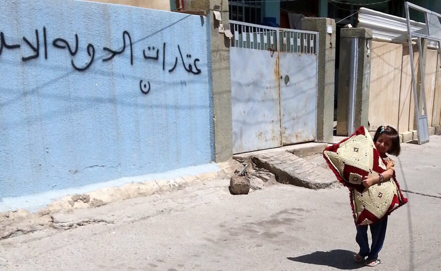 An Iraqi child walks next an empty house of a Christian family in Mosul on Aug. 8. The Arabic writing on the wall reads 'Real Estate of the Islamic State.' The extremist group took control of Mosul, Iraq's second largest city, in June.