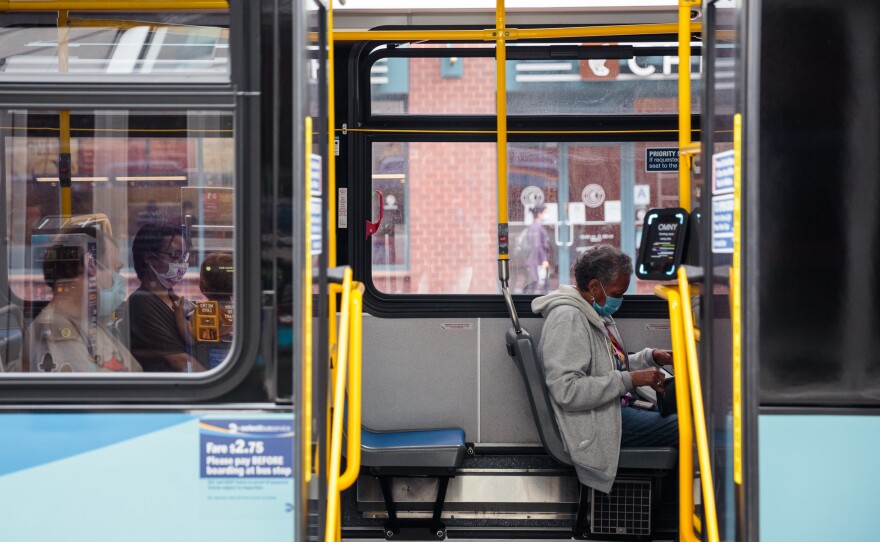 Passengers wearing protective masks sit inside a bus while waiting by Union Square in New York City.