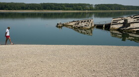 A man walks on a sandbank by the wreckage of a WWII German warship, which emerged during the drought in front of Djerdap II, a large dam on the Danube River between Romania and Serbia near Prahovo on Aug. 4, 2026.