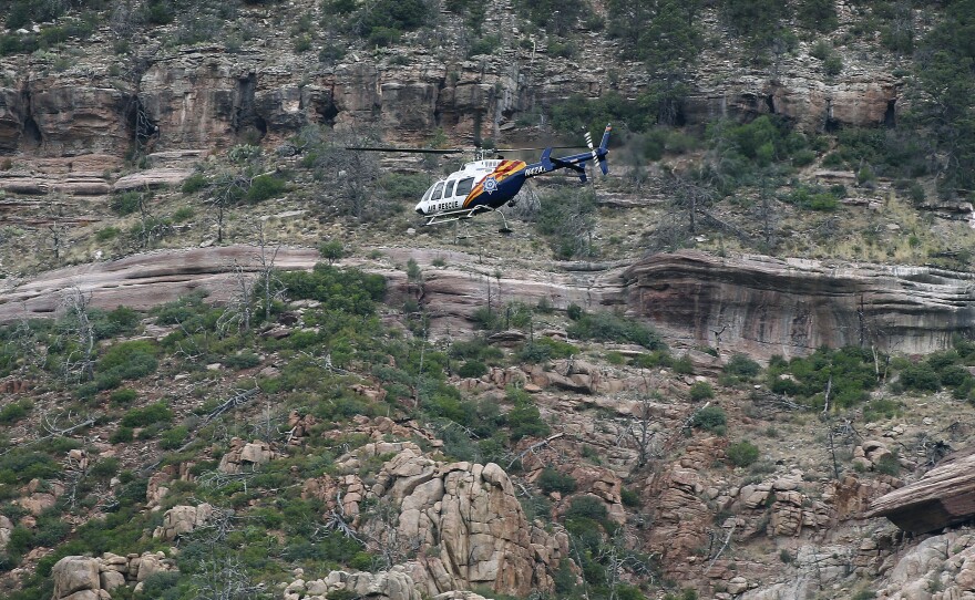 A helicopter flies above the rugged terrain along the banks of the East Verde River during a search and rescue operation for victims of a flash flood on Sunday in Payson, Ariz. Search and rescue crews recovered bodies of five adults and four children.