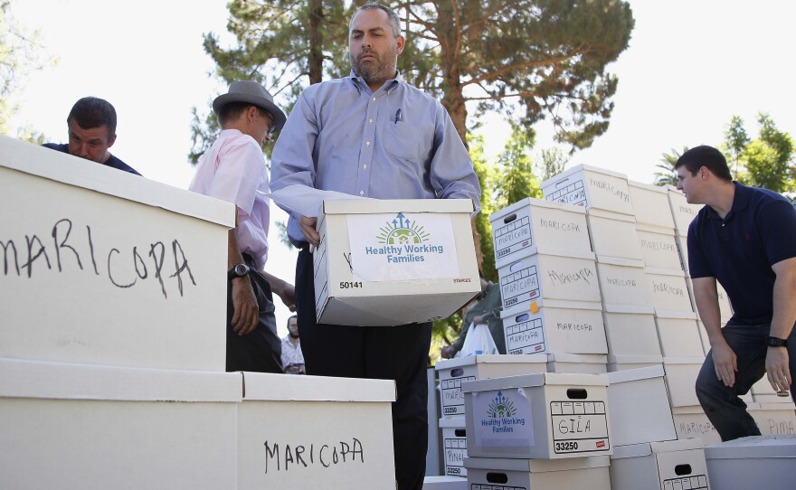 State Elections Director Eric Spencer helps arrange petitions being delivered to the Capitol by advocates of raising Arizona's minimum wage on July 7, 2016, in Phoenix.