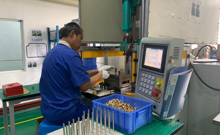 A worker at Thinova Magnet Co. Ltd. puts rare earth magnets into a press at a factory in Zhejiang province.