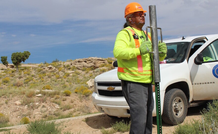 M.C. Baldwin, working for the Navajo Nation Rural Addressing Authority, installs a pair of street signs along BIA road 5020.