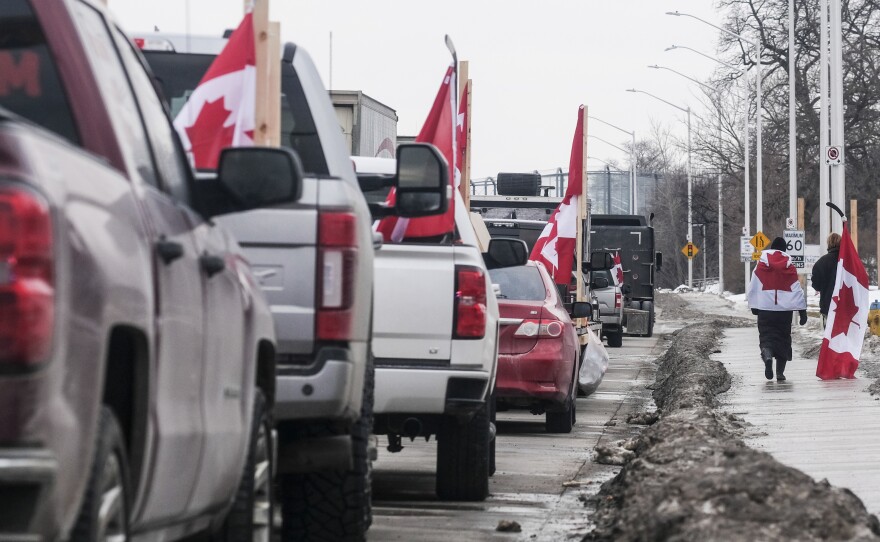 Protesters with trucks and other vehicles adorned in signs and Canadian flags gather near Ambassador Bridge on February 9 in Windsor, Canada. The bridge is the busiest land border crossing in North America in terms of trade volume.