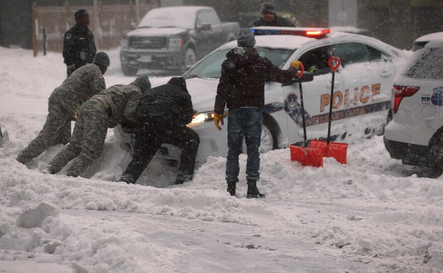 National Guard members and other people help to push a police car that got stuck in the snow on January 23 in Washington, D.C. Heavy snow continued to fall in the Mid-Atlantic region causing "life-threatening blizzard conditions" and affecting millions of people.