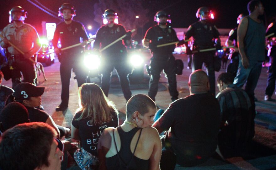 Protesters sit in front of a police line in El Cajon, a suburb of San Diego, Calif., on Wednesday night.