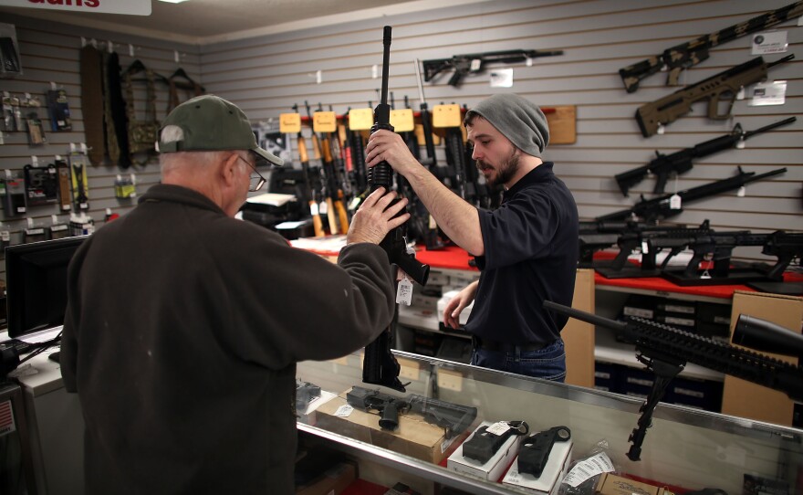 Jared Treadway, 26, a sales associate at Northwest Armory in Portland, shows a customer an AR-15 rifle Tuesday in the store's showroom.
