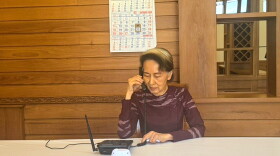 In this photo released by Myanmar's government on Thursday, Myanmar's ousted leader Aung San Suu Kyi talks on the phone with her son Kim Aris, in Naypyidaw, Myanmar.