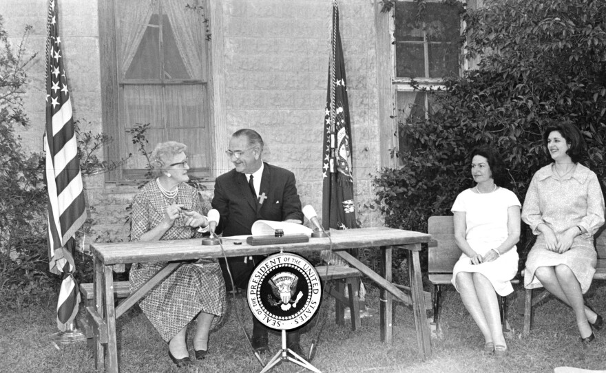 President Lyndon B. Johnson jokes with his first-grade teacher, Kate Deadrich Loney, after signing the Elementary and Secondary Education Act near Stonewall, Texas, on April 11, 1965. Seated at right are first lady Ladybird Johnson and daughter Lynda Bird.