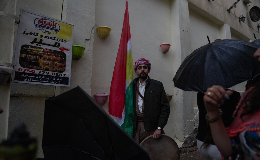 Ismail Mohammad, 28, holds a Kurdish flag and a drum as people pass by at the Nowruz festivities.