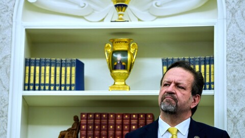 Sebastian Gorka listens as President Donald Trump speaks with reporters after signing executive orders in the Oval Office of the White House, April 23, 2025, in Washington.