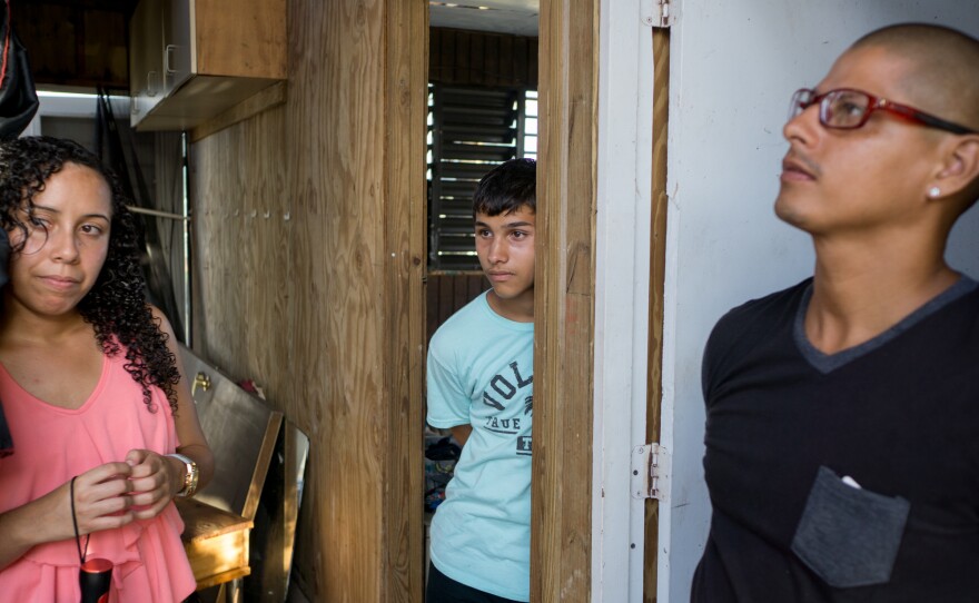 Liz Vazquez Ojeda and her boyfriend Angel Joel Alvarez Lopez stand with his son Angel Alvarez Morales, 14, inside their wood house. "Next time I build, I'm going to build cement walls," Lopez says.