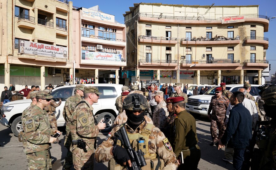 Iraqi soldiers stand watch on the outskirts of the group as Renforth and Rubaie mingle with Iraqis in the street.