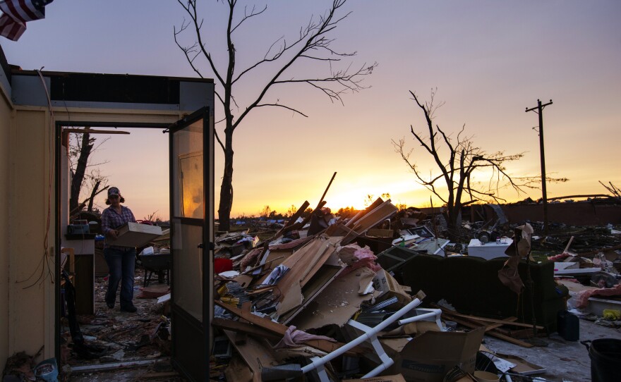 Rita Green carried a plastic bin of items as she helped a family friend salvage things from a home Thursday in Moore, Okla.