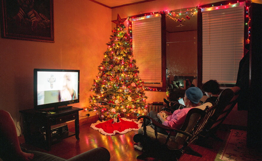 Teresa Chavez watches an episode of La Rosa de Guadalupe as her grandchildren look at their phones in 2024.