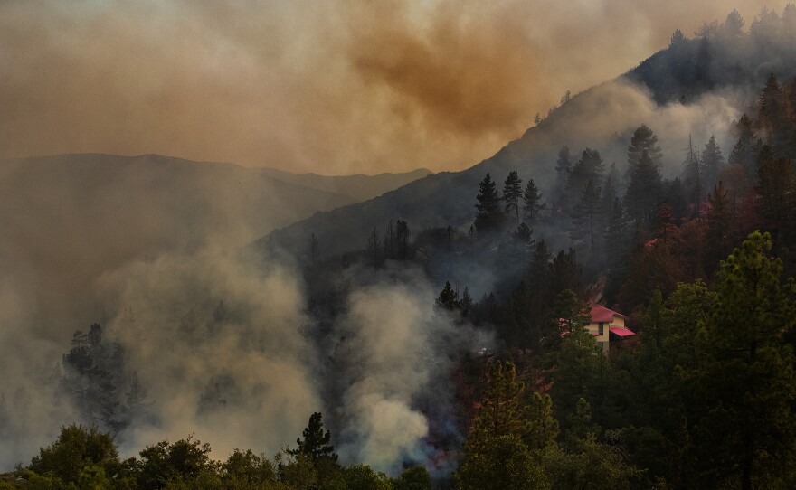 A house is covered in pink fire retardant as the Cranston Fire burns out of control near the town of Idyllwild in the San Bernardino National Forest on Wednesday.