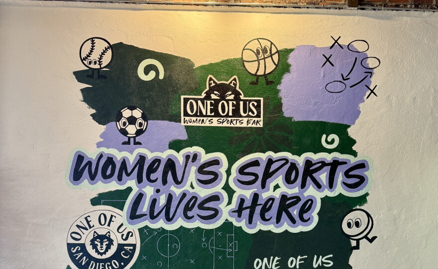A mural designed by FemmeFolio Design Studio and painted by Allison Hunsley serves as the centerpiece of a standing-room-only area of One of Us in North Park on July 22, 2026.