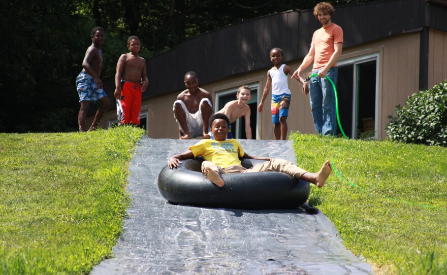 During the day, the kids visit their dads in prison. But in the late afternoon and evenings, they do activities like tubing down a giant slip-and-slide. Kobe Goodall takes his turn while his fellow campers look on.