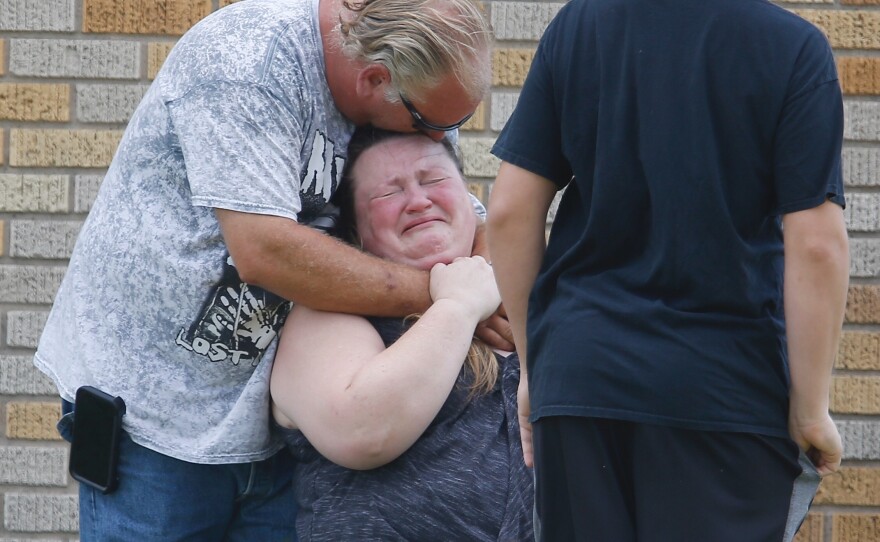 A man hugs a woman outside the Alamo Gym where parents wait to reunite with their kids following a shooting at Santa Fe High School.