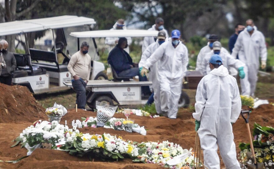 Several COVID-19 burials are performed in the Vila Formosa Cemetery on the east side of São Paulo, Brazil, on Sunday. Brazil, which reported a large spike in cases on Monday, now ranks second after the U.S. for total infections and deaths.