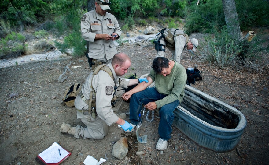 Border Patrol agents help an ailing migrant crosser.