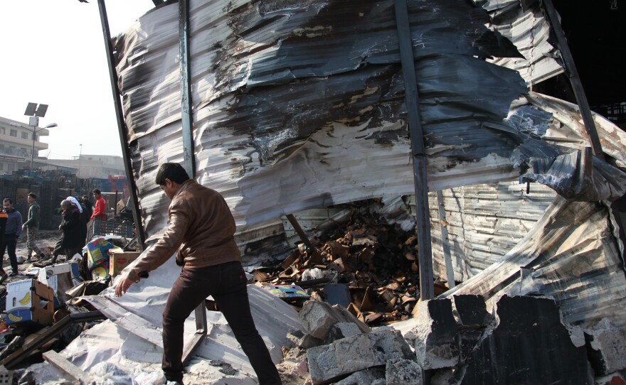 Iraqis inspect the scene of a Sunday car bomb attack at a Baghdad market.