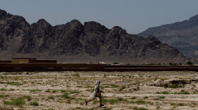 An Afghan girl runs across the desert as the mountains bordering Kandahar valley loom in the background on June 6, 2010 in Rambazi, a village south of Kandahar, Afghanistan.