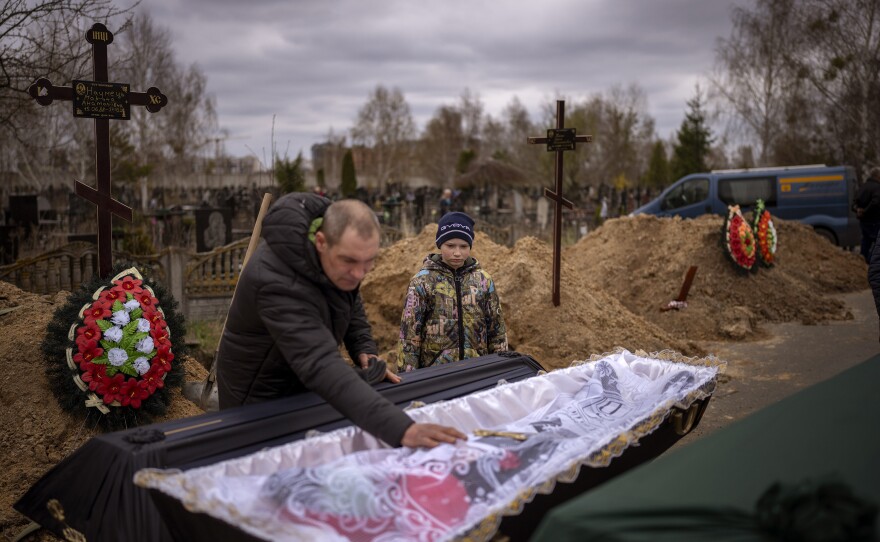 <strong>April 20:</strong> Vova, 10, looks at the body of his mother, Maryna, lying in a coffin as his father, Ivan Drahun, prays during her funeral in Bucha, a suburb of Kyiv, Ukraine. Maryna died as the family sheltered in a basement for more than a month amid Russia's occupation.