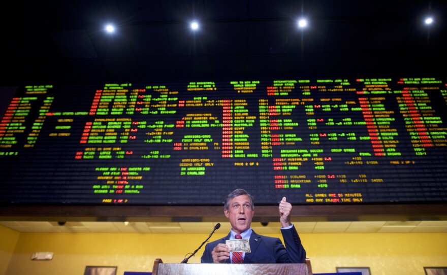 Delaware Gov. John Carney holds a $10 bill he used to place the first bet at Dover Downs Casino on Tuesday in Dover, Del. Delaware is the first state to launch legal sports betting since a Supreme Court decision allowed states to legalize such gambling.