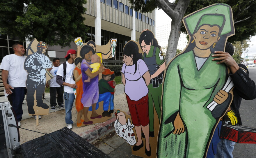 Members a coalition of Latino groups hold posters of immigrant workers and Dream Act students as they join a pro-immigrant rally outside the Federal Building in Los Angeles, March. 26, 2014. 