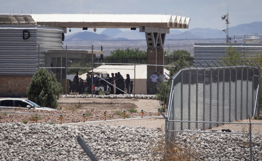 People wait outside the port of entry at Tornillo, Texas, in June 2018. Beyond them is one of the tents that were put up to house unaccompanied migrant children.