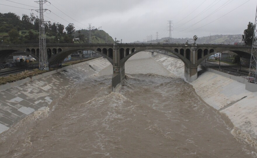 The rain-swollen Los Angeles River flows near downtown Los Angeles on Saturday, as a powerful storm pounds Southern California.